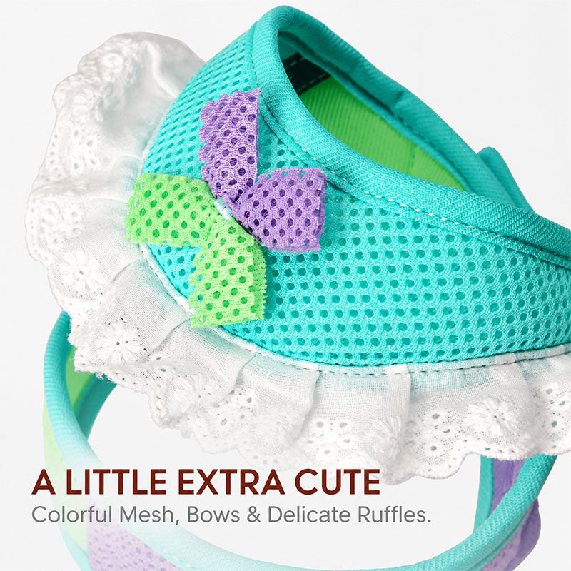 Close-up of a mint turquoise mesh dog harness showing its perforated fabric, lavender and lime green bow, and white lace ruffle trim.